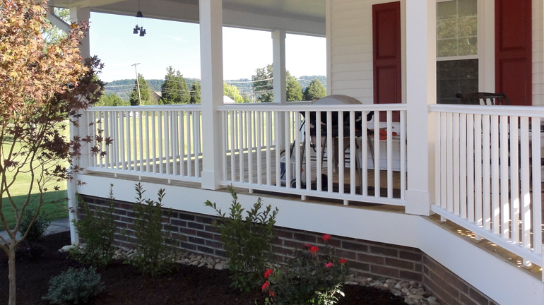 Wraparound porch with Deckorators CXT Pro Composite Railing in white featuring Colonial Style Top Rail installed between square columns with square composite balusters