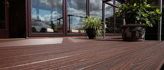 planters sitting on Trex deck with Transcend Decking in spiced rum and glass doors with the sky in the reflection