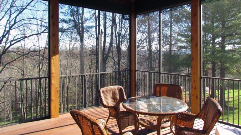 Screened-in porch with wicker dining set overlooks a wooded yard, between 8x8 cedar framing is Westbury ScreenRail in Bronze Fine Texture finish