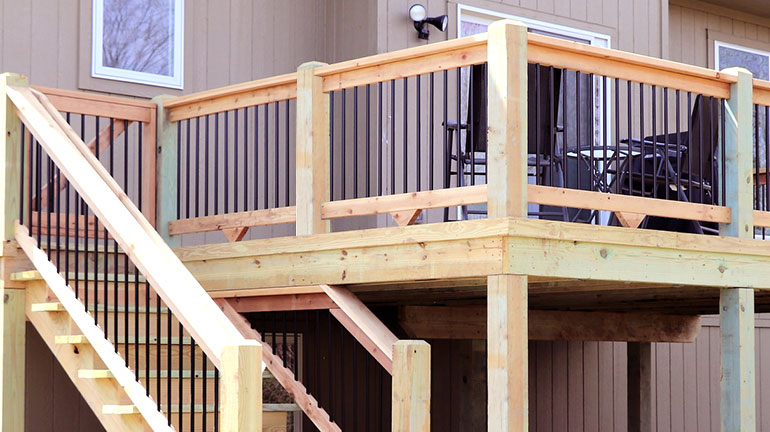 A 2nd-story deck made of wood with wood railing and balusters
