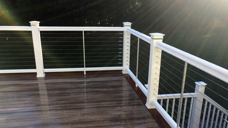 TimerTech RadianceRail composite railing in white on top of a dark deck with sunshine.