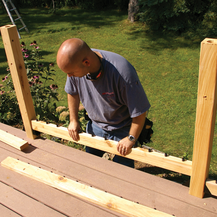 Blair places bottom cedar railing into place with already installed railing connectors