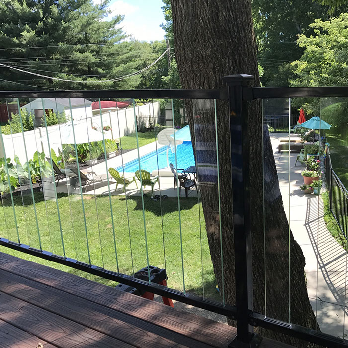 Composite deck overlooks a backyard pool, the view made possible because of the Fortress FE26 Iron Rail system in gloss black with clear PureView Glass Balusters