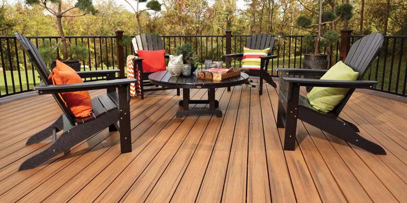 A bright, sunny composite deck is set up for company with deck chairs and a table