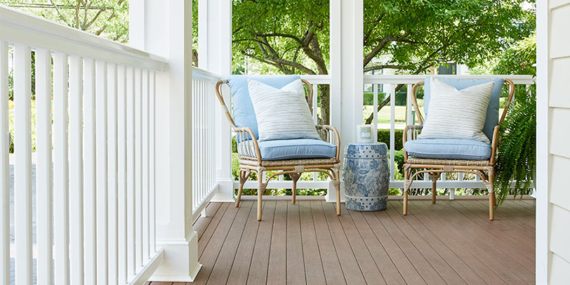 A cozy modern farmhouse front porch with brown porch boards and classic white railing