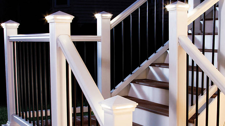 A staircase is illuminated by Pyramid LED Post Cap Lights by Trex Lighting in Classic White