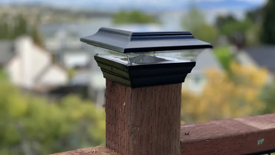 A solar post cap light placed on top of a cedar deck post