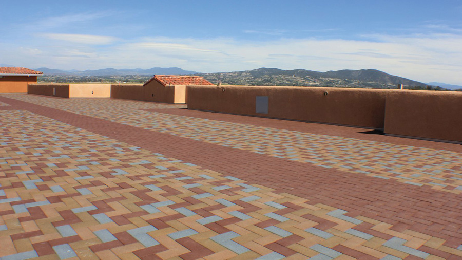 A large rooftop deck with a walkway built into its paver pattern