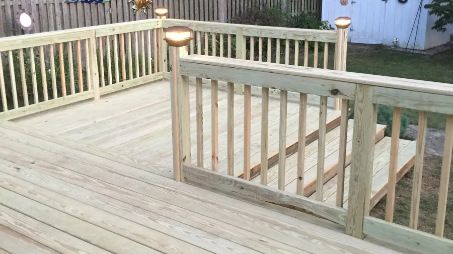 A bright wood deck with lighted post caps installed on each post 