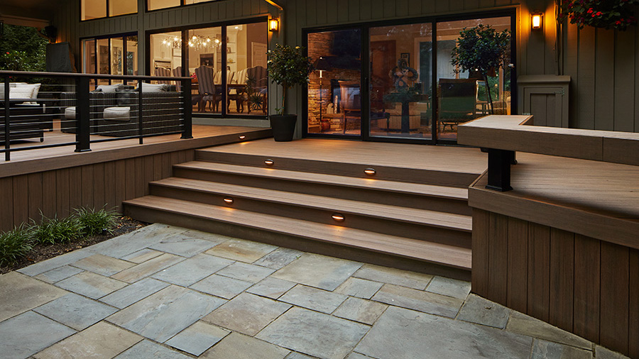 A rich mid-century modern deck with warm lighting and cable railing