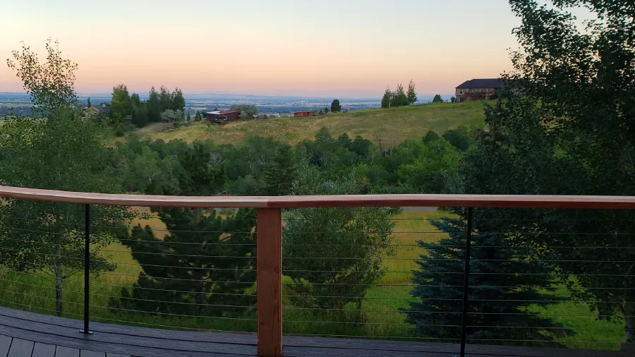 A deck with a forest view highlighted by sleek cable railing