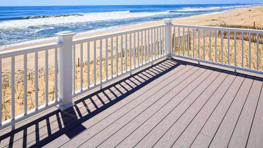 A bright, classic white deck railing near a beach