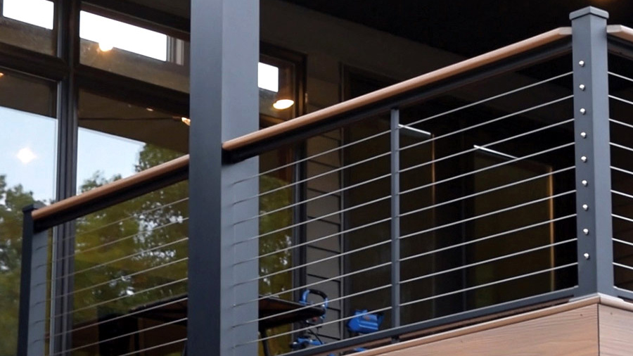 A modern home with AFCO cable deck railing, using a deck board as a functional drink rail