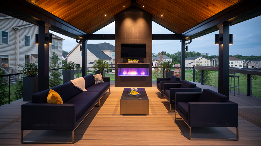 A stunningly modern covered deck, complete with wood-paneled ceiling and a fireplace