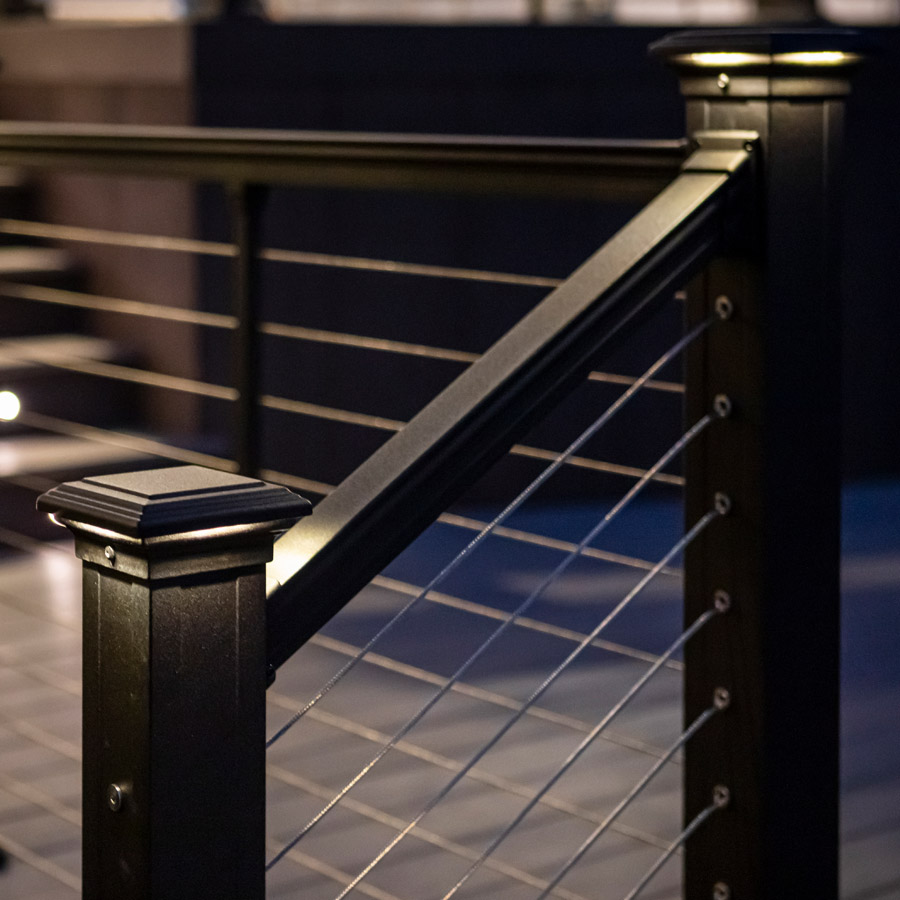 A matte black metal railing with cable runs and lighting
