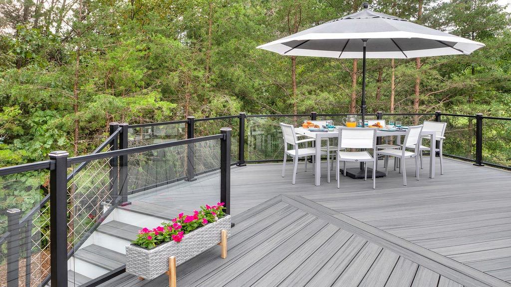 Pink flowers pop on a gray deck with modern deck railing