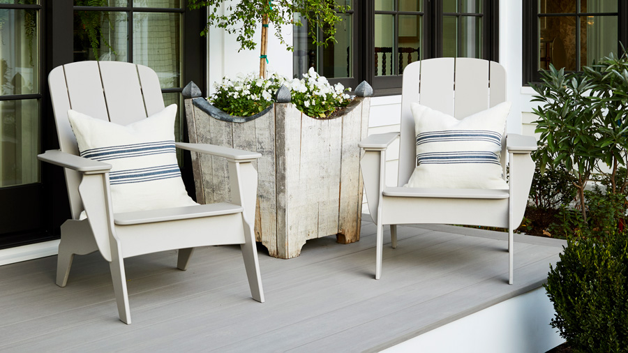 Two TimberTech Adirondack chairs in the off-white Canvas color sit near a reclaimed wood planter