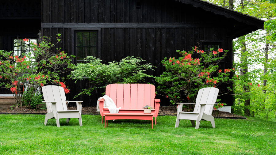 A mix of Coral and Canvas TimberTech Outdoor Furniture in front of a black house