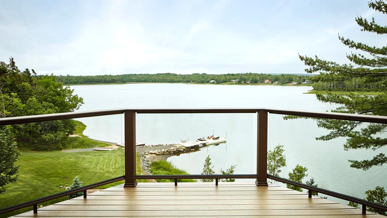 A panoramic lake view seen through glass deck railing
