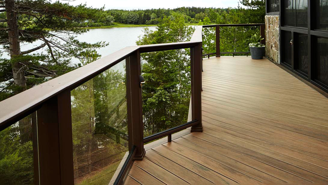 A narrow deck uses glass railing and a functional drink rail to feel larger