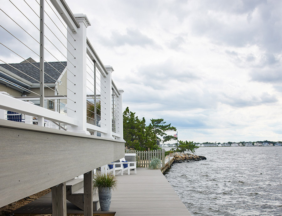 A white cable deck railing rises high above Coastline fascia boards and an inviting lake