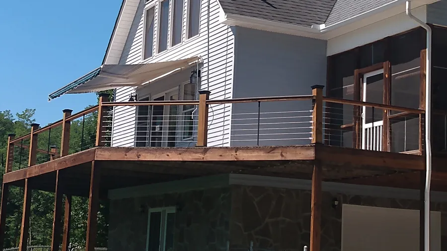 A wood deck railing after the owner replaced wood balusters with modern cable runs