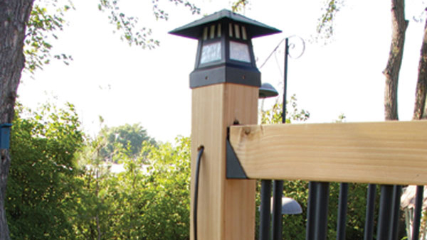 The wire for a lighted post cap runs into the top of a wood post, then out a small hole drilled in the side of the post