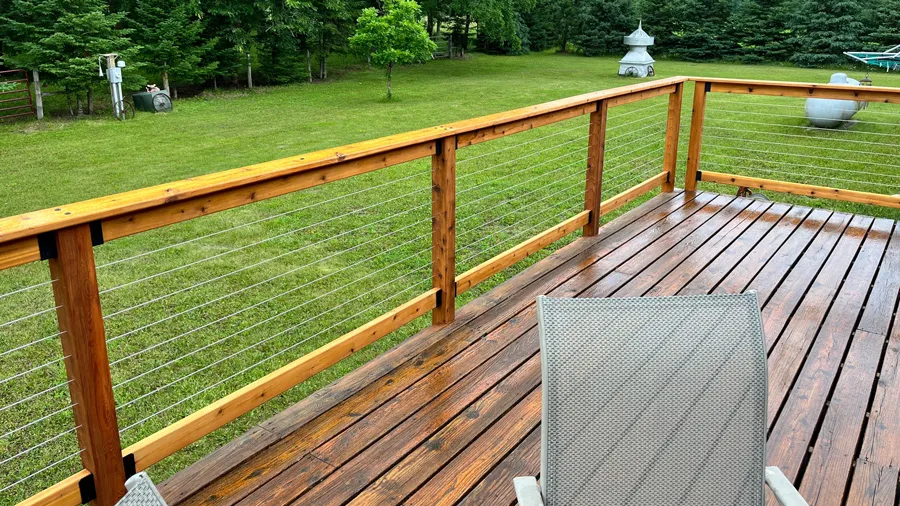 A brand new wood railing with cable between the wood posts and rails