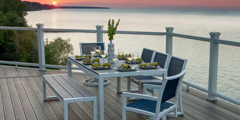 A luxurious glass railing on a deck overlooking an ocean at sunset