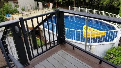 A poolside deck with a safety deck gate installed at the top of the stairs