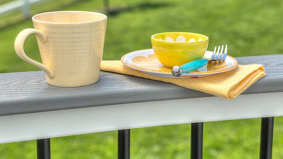 A drink rail deck railing with a coffee mug and breakfast bowl