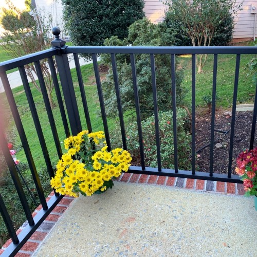 The clean look of rich, black Westbury Tuscany metal stair railing looks great against the brickwork of the home